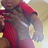 arm, baby, bright_color, casual, ceiling, child, cute, expression, fluorescent_light, hand, holding, indoor, infant, person, playful, portrait, red_clothing, skin, tongue_out, young_child