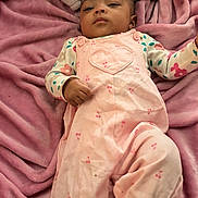 Damarionna is registered to the contest to win money with this photo: baby, child, infant, pink_overalls, heart_design, blanket, plush, soft_texture, lying_down, cute, face, portrait, clothing, indoor, young_child, sleepwear, comfortable, resting, person, casual