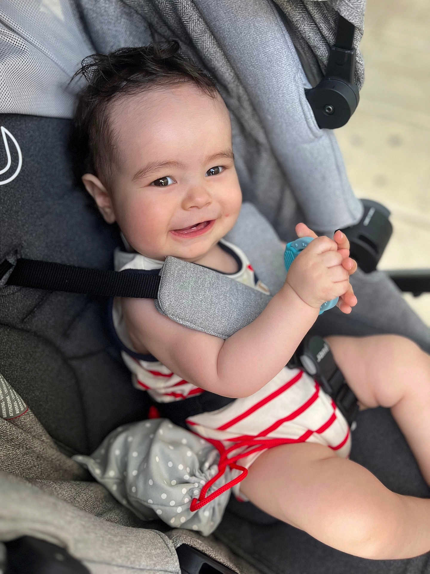 Nahël a rejoint le concours — aidez-le/la à gagner de superbes lots ! baby, smiling, stroller, toy, striped_clothing, child, infant, seatbelt, happy, cute, hand, face, cheerful, comfort, indoor, person, plush, head, eyes, skin
