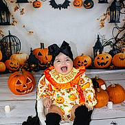 Alarni-Mae joined the competition — help win amazing prizes! autumn_leaves, baby, black_bow, black_socks, celebration, child, costume, cute, decorations, festive, halloween, holiday, indoors, jack_o_lantern, lantern, orange, pumpkin, sitting, smiling, spooky