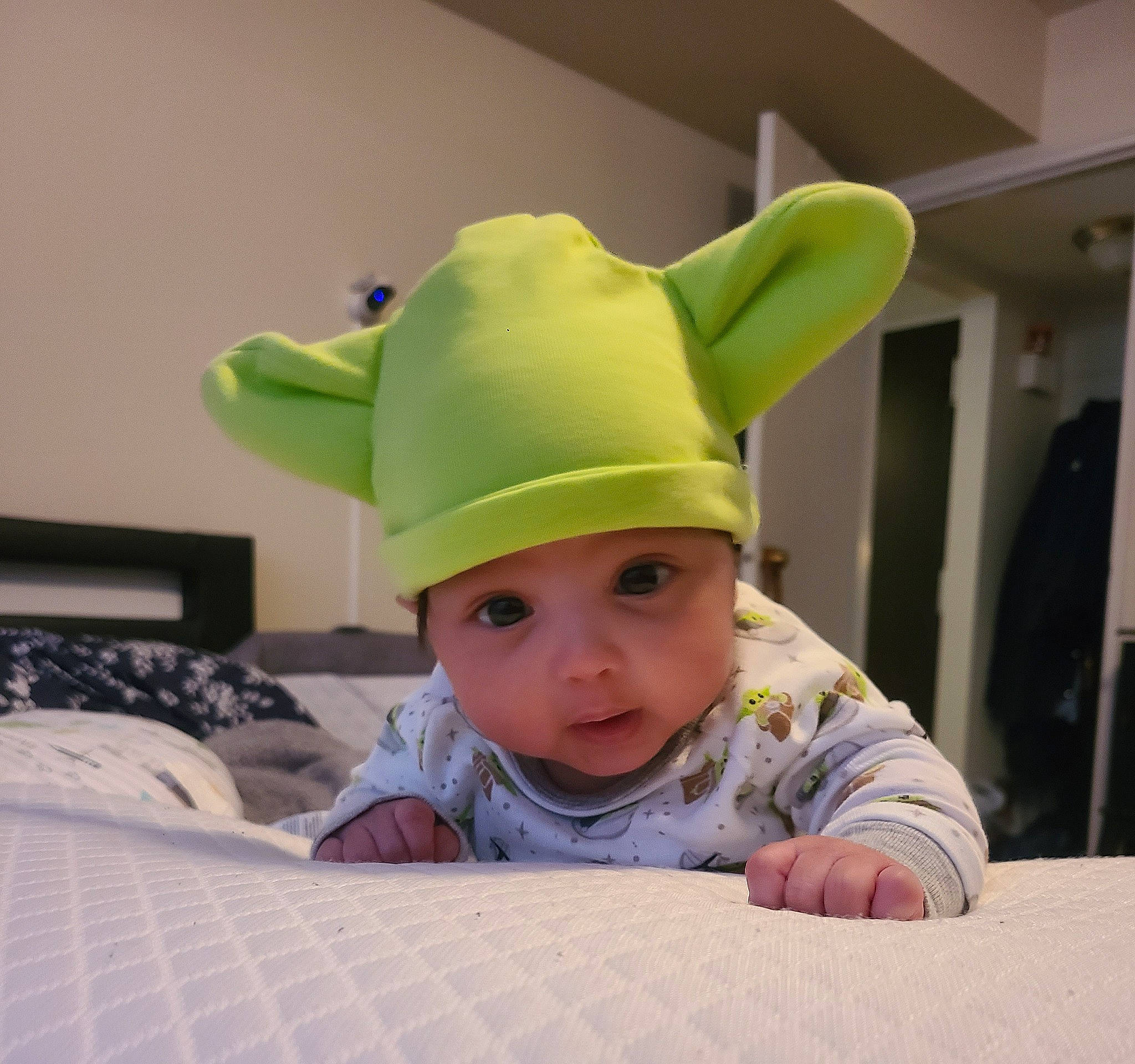 Evan is registered to the contest to win money with this photo: baby, baby_toddler_clothing, cap, child, comfort, costume_accessory, costume_hat, face, fashion_accessory, flooring, fun, happy, headgear, headwear, linens, party_supply, person, room, sitting, sleeve