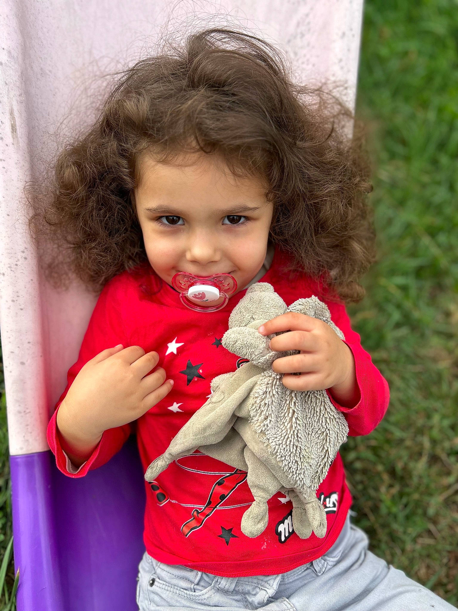 Elisa a rejoint le concours — aidez-le/la à gagner de superbes lots ! baby, baby_toddler_clothing, beak, child, doll, eye, face, fun, gesture, grass, hand, happy, joy, nail, people_in_nature, person, red, sitting, skin, stuffed_toy