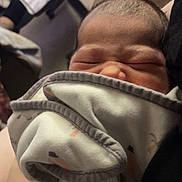 Liora is registered to the contest to win money with this photo: newborn, baby, infant, sleeping, scrunched_face, swaddled, blanket, wrapped, portrait, close_up, indoors, held, adult, stroller, clothing, textile, cozy, peaceful, family, photography
