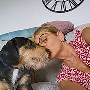 Sam participe au concours pour gagner de l'argent avec cette photo : woman, dog, couch, kiss, glasses, clock, cushion, indoor, pet, love, affection, casual_clothing, short_hair, nose_to_nose, relaxing, furniture, home, portrait, animal, human