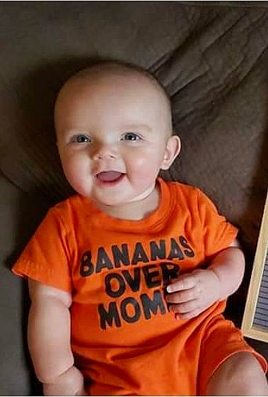 Hunter is registered to the contest to win money with this photo: baby, baby_toddler_clothing, cheek, child, chin, clothing, comfort, fun, happy, mouth, neck, nose, orange, person, sitting, skin, sleeve, smile, t_shirt, toddler