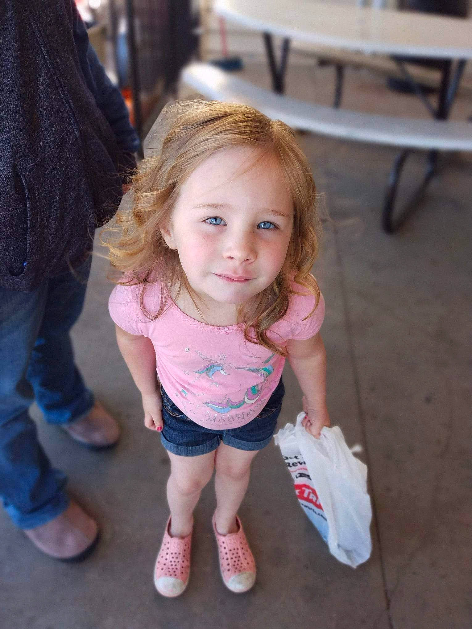 Lydia-ann is registered to the contest to win money with this photo: baby_toddler_clothing, child, event, eye, foot, fun, happy, human_leg, iris, joy, leisure, person, sandal, shoe, shorts, sitting, skin, smile, sneakers, t_shirt