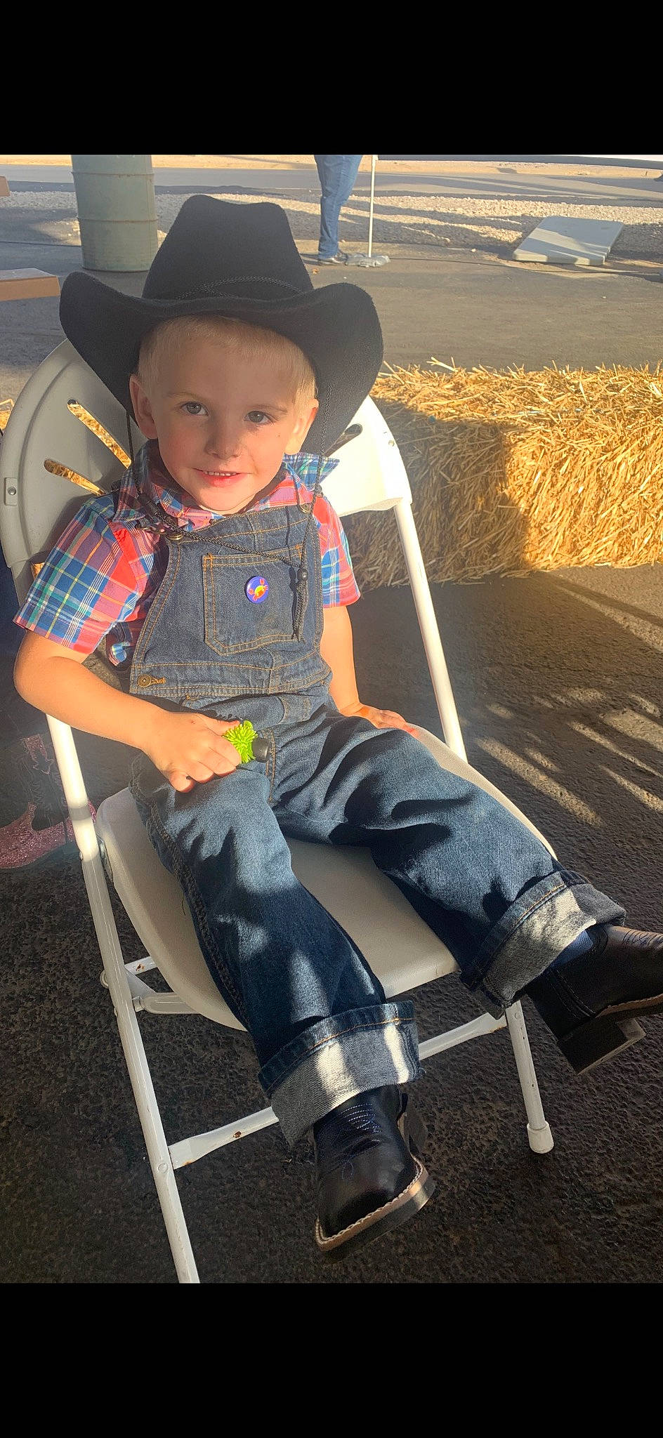 Charlie is registered to the contest to win money with this photo: automotive_tire, automotive_wheel_system, cap, chair, cowboy_hat, denim, electric_blue, fashion_accessory, fedora, fun, hat, human_leg, joy, leisure, light, person, sitting, sun_hat, thigh, toddler