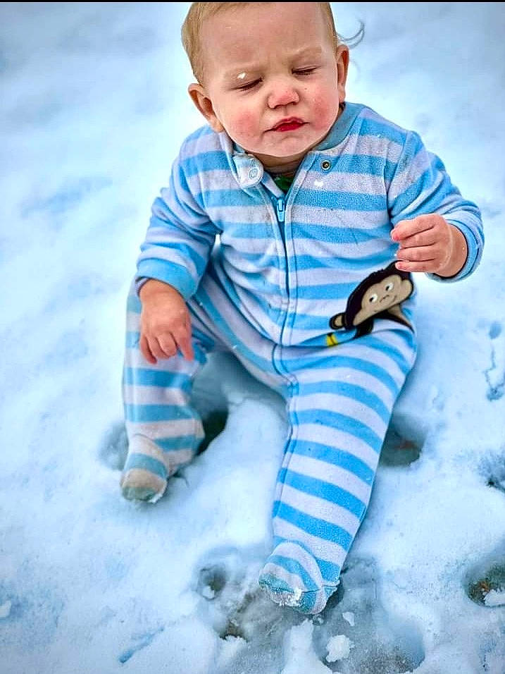 Zane is registered to the contest to win money with this photo: baby, baby_toddler_clothing, blue, child, electric_blue, freezing, fun, gesture, grass, happy, leg, pattern, people_in_nature, person, portrait_photography, sitting, sleeve, snow, sorrow, thumb