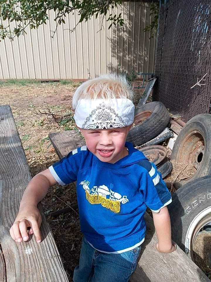 Brentyn is registered to the contest to win money with this photo: asphalt, automotive_tire, cap, electric_blue, eyewear, fun, grass, headgear, headwear, leisure, person, plant, rim, smile, soil, synthetic_rubber, t_shirt, tire, tire_care, toddler