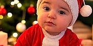 Solann participe au concours pour gagner de l'argent avec cette photo : baby, celebration, child, christmas, christmas_lights, christmas_tree, cute, decorations, festive, holiday, holiday_outfit, holiday_season, indoors, infant, ornaments, portrait, red_clothing, santa_hat, seasonal, sitting