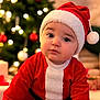 Solann participe au concours pour gagner de l'argent avec cette photo : baby, child, christmas, santa_hat, red_clothing, holiday, festive, indoors, christmas_tree, ornaments, decorations, cute, infant, portrait, holiday_season, seasonal, celebration, christmas_lights, sitting, holiday_outfit