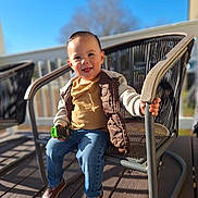 Dereck Sagastume is registered to the contest to win money with this photo: blue_sky, blurred_background, brown_shoes, casual_clothing, child, daytime, happy, jacket, jeans, metal_chair, outdoor, patio_chair, person, playtime, sitting, smiling, sunlight, toddler, toy_car, wooden_deck