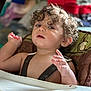 Lucas joined the competition — help win amazing prizes! child, toddler, curly_hair, high_chair, indoor, person, face, expression, skin, hand, furniture, seat, clothing, straps, table, mouth, eyes, nose, ear, background