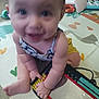 baby, child, play_mat, toy, mirror, floor, indoor, colorful, smiling, happy, sitting, clothing, arm, hand, foot, reflection, background, carpet, infant, person