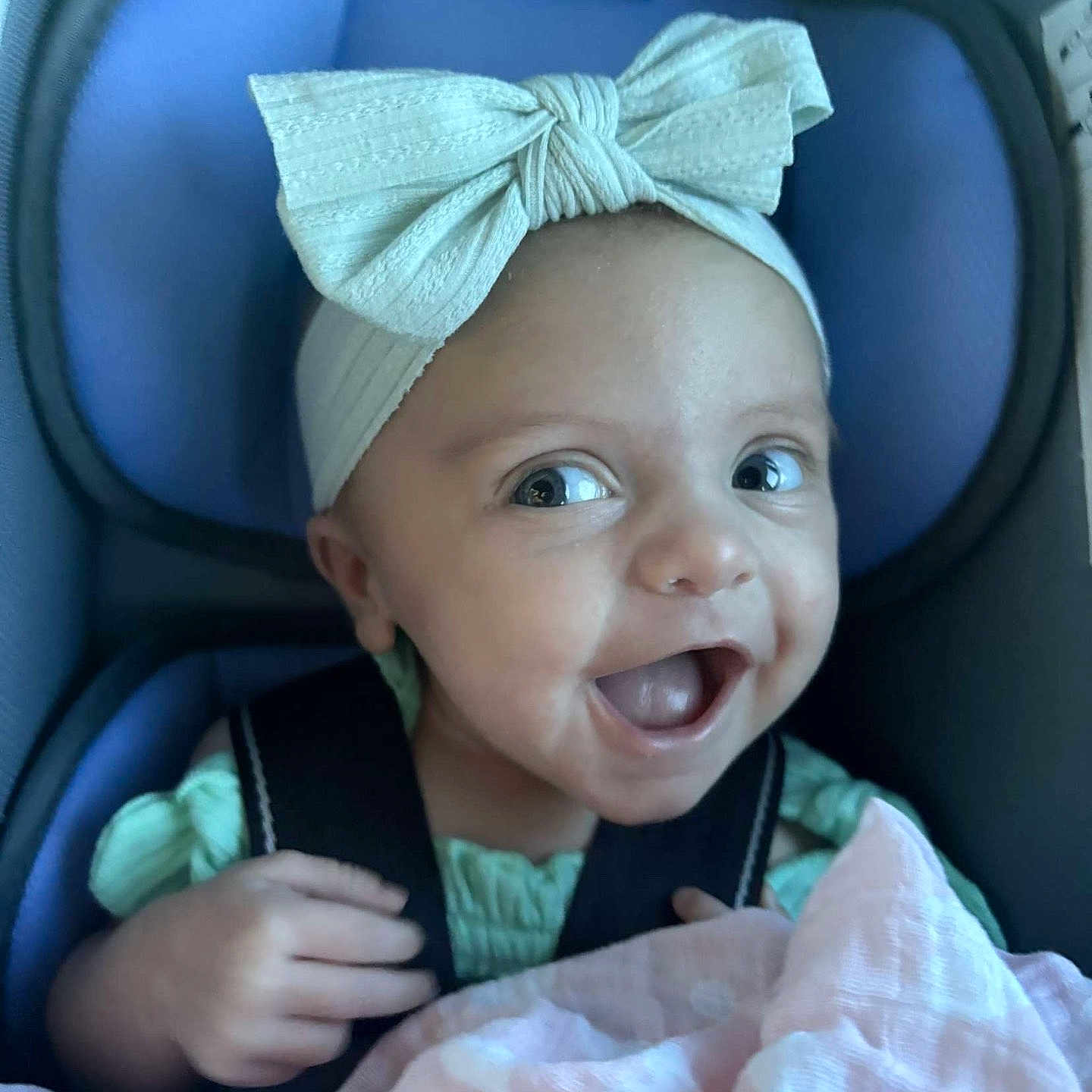 Emma joined the competition — help win amazing prizes! baby, blanket, bow, car_seat, child, closeup, clothing, cute, expression, face, hand, happy, headband, indoors, infant, person, portrait, seatbelt, smile, young_child