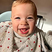 Augustin participe au concours pour gagner de l'argent avec cette photo : baby, smiling, face, bib, heart_pattern, food, highchair, indoor, child, happy, cute, portrait, skin, mouth, eyes, clothing, infant, person, light, texture