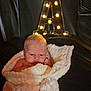 baby, blanket, infant, face, lighting, dark_background, cozy, cute, portrait, newborn, wrapped, soft_texture, glowing_letter, warm_light, indoor, resting, young_child, expression, skin, head