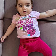 Meryem a rejoint le concours — aidez-le/la à gagner de superbes lots ! adorable, baby, casual_clothing, child, comfortable, couch, cute, earrings, expression, eyes, face, indoors, infant, leggings, love_message, lying_down, pink_shirt, soft_furniture, sparkle_text, winking_heart