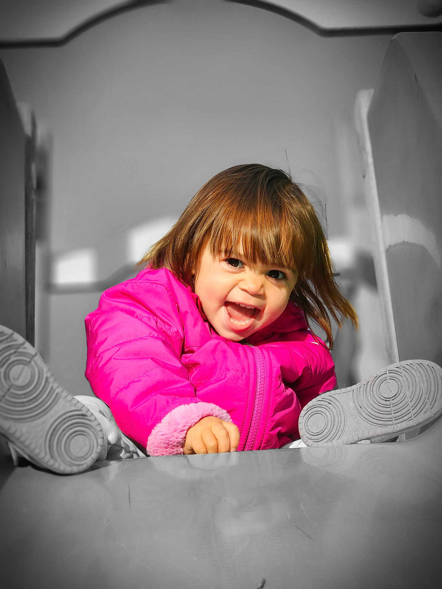 Max participe au concours pour gagner de l'argent avec cette photo : child, toddler, pink_jacket, slide, playground, smiling, happy, outdoor, fun, winter_clothing, young_child, play, joyful, face, feet, hair, casual_wear, expression, activity, daylight