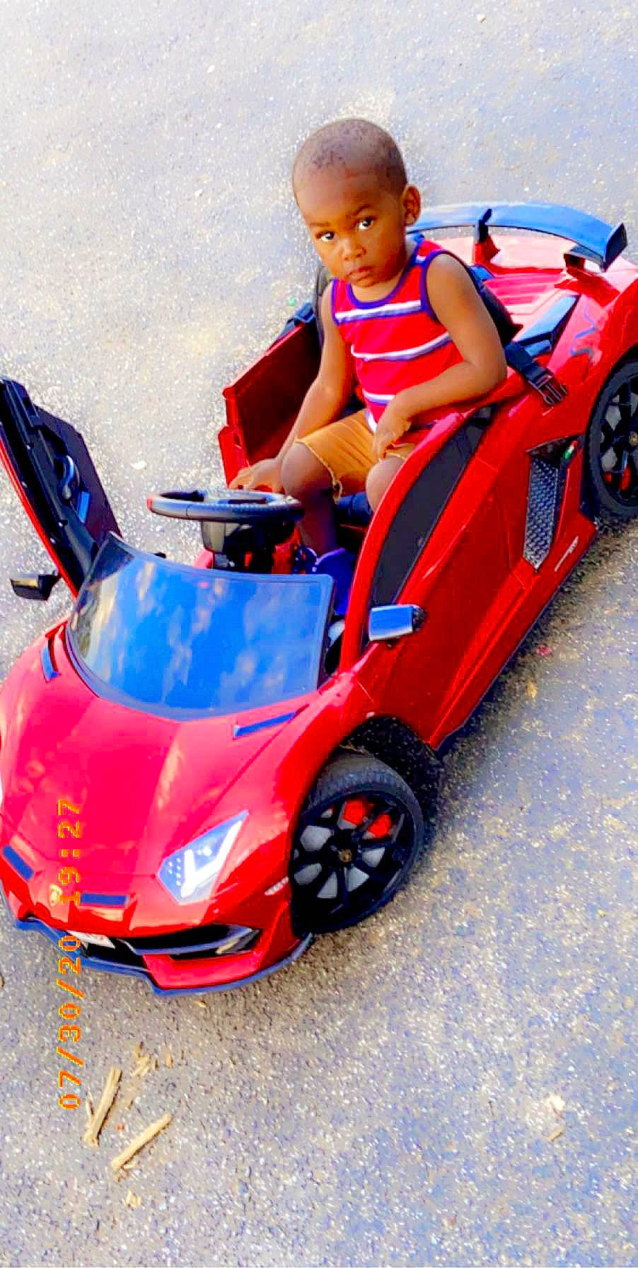 Grayson is registered to the contest to win money with this photo: automotive_design, automotive_exterior, automotive_fog_light, automotive_tire, automotive_wheel_system, bumper, car, fender, hood, kit_car, motor_vehicle, motorsport, person, racing, red, riding_toy, tire, toddler, toy, vehicle