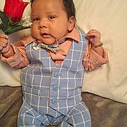 Immanuel is registered to the contest to win money with this photo: adorable, baby, bear_face_socks, blue_vest, bow_tie, bracelet, child, cute, expression, fashion, hand_holding, indoors, infant, knitted_socks, lying_down, peach_shirt, plaid_pants, portrait, rose, soft_surface