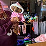 Precious is registered to the contest to win money with this photo: dog, pet, hoodie, pink_clothing, woman, holding, kitchen, cereal_boxes, stove, oven, towels, refrigerator, smiling, sweater, counter, food, indoor, small_dog, table, human_hand