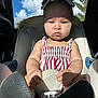 Coi is registered to the contest to win money with this photo: baby, blue_sky, bows, car_interior, car_seat, child, clouds, face, hands, infant, pigtails, portrait, safety_buckle, seatbelt, serious_expression, shadow, striped_dress, sunlight, window, young_child