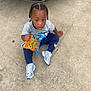 child, toddler, snack, cheetos, puffs, braids, sneakers, new_balance, gray_shirt, blue_pants, concrete, car, outdoor, sitting, curious, food, street, casual, young_child, daylight