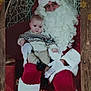 baby, child, santa_claus, christmas, holiday, festive, beard, red_suit, glasses, gloves, sweater, chair, decorations, pinecones, gift, portrait, indoor, smiling, seasonal, celebration
