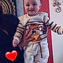 Fabio participe au concours pour gagner de l'argent avec cette photo : baby, child, smiling, striped_sweater, tiger_print, pants, socks, person, hand, indoor, wall_art, decor, red_wall, gray_wall, blanket, holding, cute, happy, standing, adult_hand