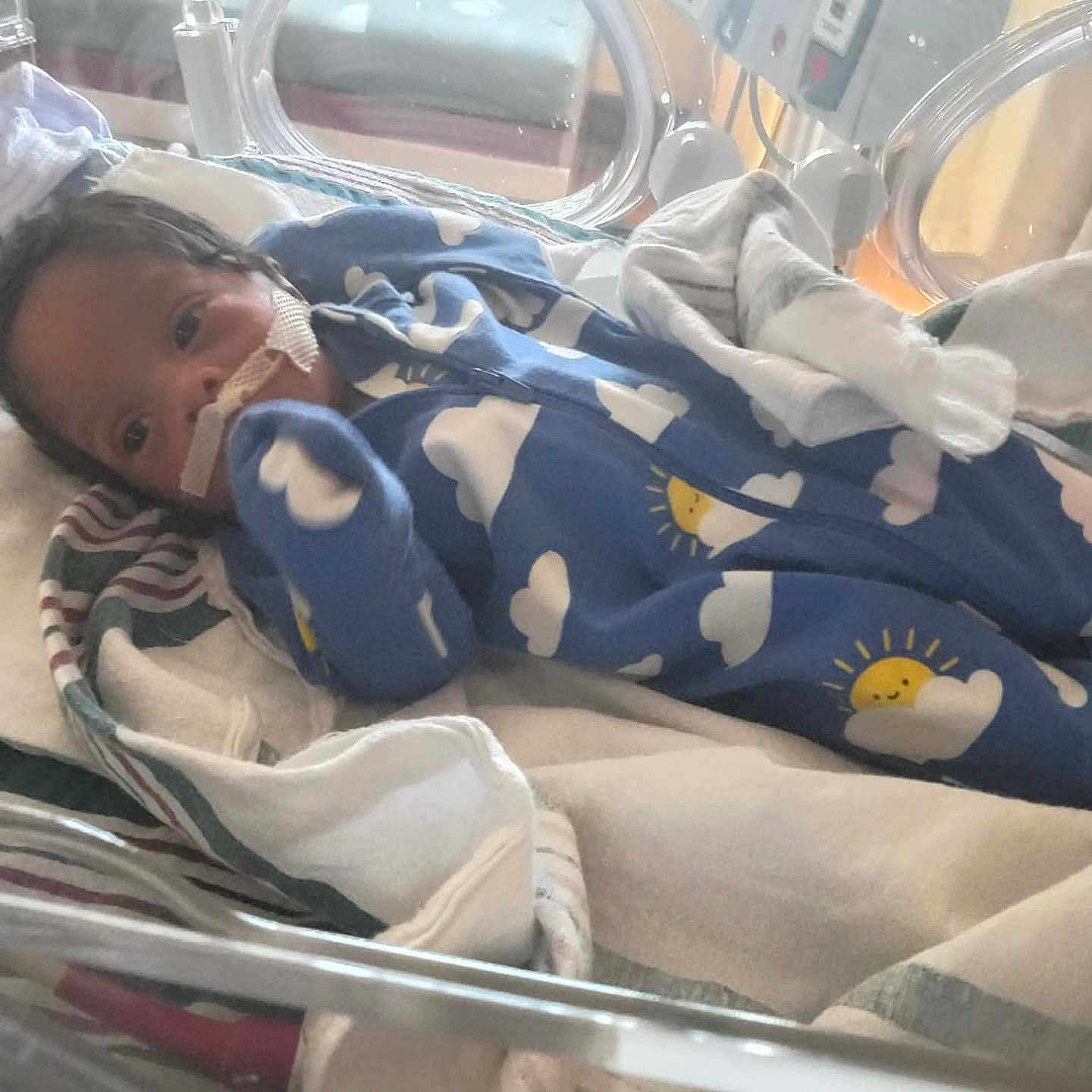 Josiah joined the competition — help win amazing prizes! baby, infant, hospital, incubator, medical_tape, blue_onesie, cloud_pattern, sun_pattern, blanket, medical_equipment, no_smoking_sign, newborn, premature_baby, crib, healthcare, patient, child, person, indoor, care