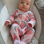 Vivian is registered to the contest to win money with this photo: baby, infant, child, onesie, watermelon_pattern, footed_pajamas, baby_bouncer, infant_seat, cushion, seat_pad, face, portrait, looking_up, wide_eyes, hands, feet, cozy, home_interior, fabric, pattern
