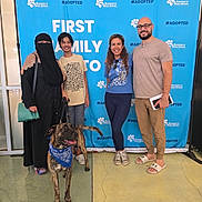 Benny joined the competition — help win amazing prizes! adoption, background, bandana, blue_backdrop, casual_clothing, diverse, dog, event, family, footwear, glasses, group, handbag, happy, indoor, people, pet, posing, smiling, standing