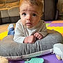 Harrison is registered to the contest to win money with this photo: baby, child, face, blue_eyes, white_sweater, cushion, toy, play_mat, indoor, living_room, carpet, expression, hands, curly_hair, soft_toys, floor, comfort, portrait, cute, curious