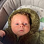 baby, infant, child, fuzzy_clothing, hood, bassinet, blanket, cushion, blue_eyes, face, hand, zipper, soft_texture, indoor, resting, cute, newborn, sleepwear, star_pattern, portrait