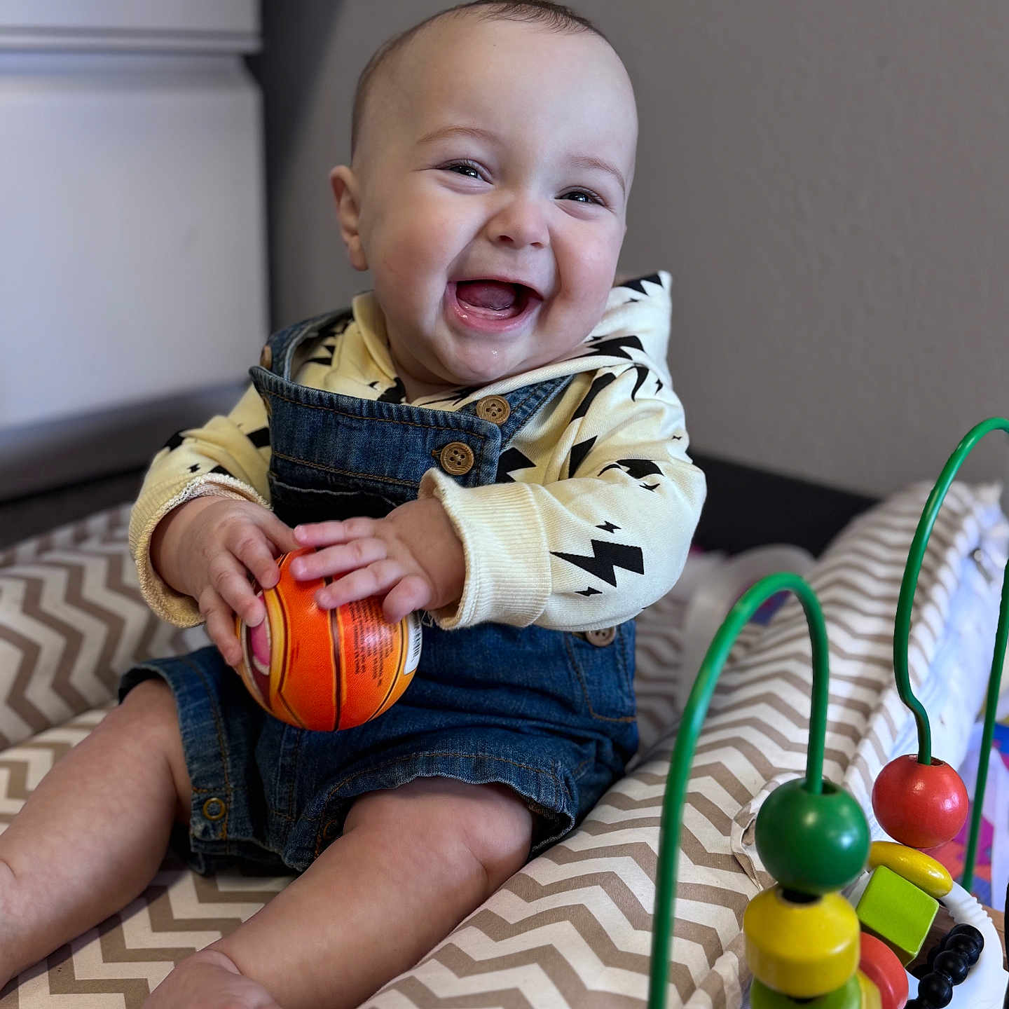 Eren is registered to the contest to win money with this photo: baby, ball, bead_maze, chevron_pattern, cute, denim_overalls, dresser, face, feet, hands, happy, indoor, infant, laughing, overalls, playmat, portrait, smiling, toy, wall