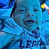 Micah joined the competition — help win amazing prizes! baby, infant, child, face, tongue, blue_light, shirt, clothing, hand, person, portrait, close_up, expression, indoor, blurred_background, holding, cute, young_child, casual, smile