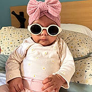 Victoire participe au concours pour gagner de l'argent avec cette photo : baby, child, sunglasses, headwrap, pink, bed, pillow, clothing, long_sleeve, pants, indoor, person, cute, fashion, accessory, portrait, hand, face, infant, cool