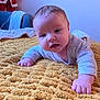 baby, blanket, child, cozy, cute, decoration, expression, face, holiday, home, indoor, infant, lying_down, person, portrait, santa_claus, soft, texture, wall_photos, yellow