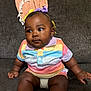 Khalani joined the competition — help win amazing prizes! baby, child, couch, blanket, colorful_clothing, striped_shirt, bow, hair_accessory, sitting, indoor, person, cute, infant, plush, furniture, portrait, happy, skin, face, expression