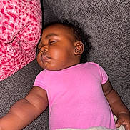 Khalani joined the competition — help win amazing prizes! baby, sleeping, pink_onesie, couch, blanket, pillow, indoor, child, peaceful, face, earrings, curly_hair, soft_texture, cozy, rest, relaxation, portrait, infant, comfort, home