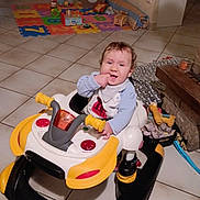 Tiago a rejoint le concours — aidez-le/la à gagner de superbes lots ! baby, child, walker, toy, floor, indoor, smiling, curly_hair, playmat, living_room, furniture, blanket, basket, candle, person, tiled_floor, happy, cute, infant, home