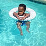 toddler, child, pool, water, life_ring, floatation_device, summer, outdoor, sunlight, reflection, swimming, baby, blue, safety, relaxation, fun, daytime, skin, hair, legs