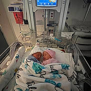 Dale is registered to the contest to win money with this photo: newborn, baby, incubator, hospital, blanket, medical_equipment, nursery, sleeping, hat, turtle_pattern, twins, bed, monitor, healthcare, indoors, cute, infant, person, sleep, cozy