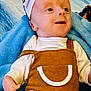 baby, infant, child, smiling, clothing, overall, hat, blanket, blue, white, happy, face, headwear, soft, cute, lying_down, indoors, person, small_hand, young