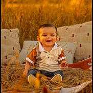 Aaron is registered to the contest to win money with this photo: baby, child, smiling, outdoor, blanket, pillow, field, grass, golden_hour, autumn, cute, portrait, sitting, warm_light, nature, jeans, shirt, happy, infant, cozy