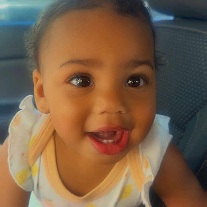 Juanita joined the competition — help win amazing prizes! baby, car, child, clothing, cute, eyes, face, hair, happy, indoors, interior, mouth, person, portrait, seat, sitting, skin, smiling, toddler, young