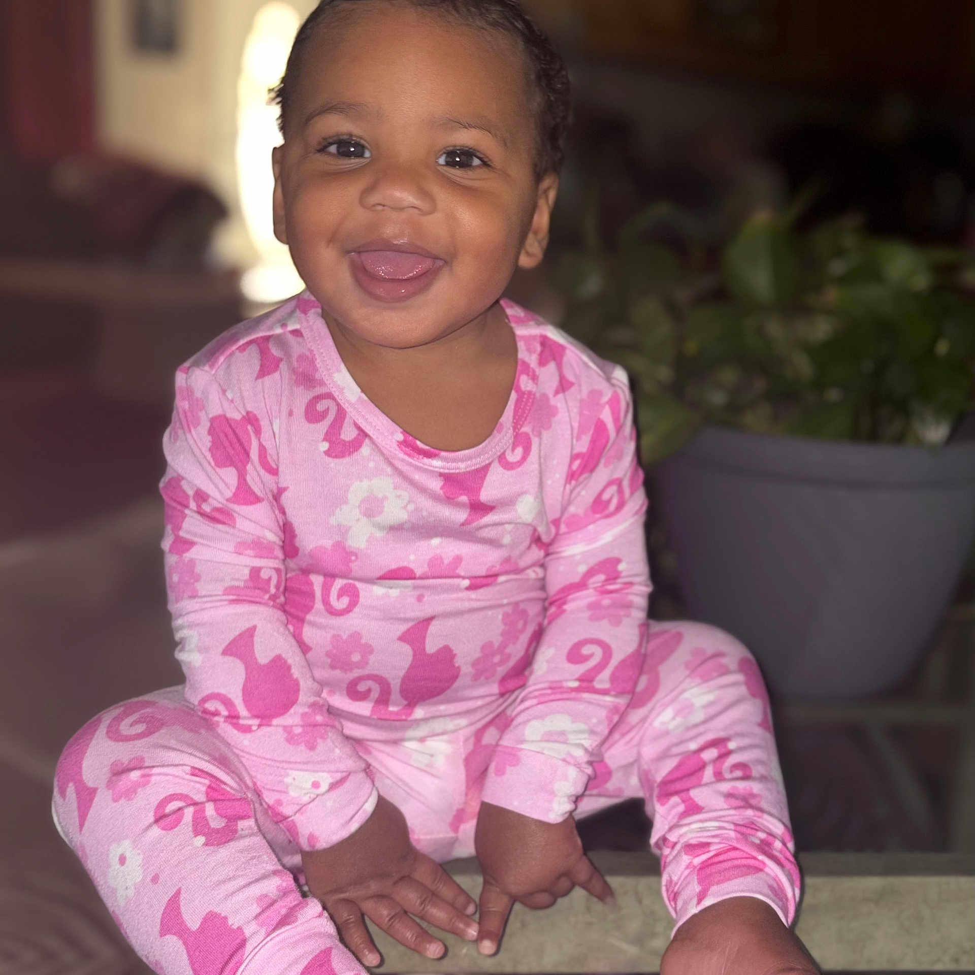 Juanita joined the competition — help win amazing prizes! toddler, child, smiling, pink_pajamas, indoor, glass_table, plant, happy, cute, sitting, portrait, face, person, home, cozy, baby, clothing, feet, tongue_out, playful