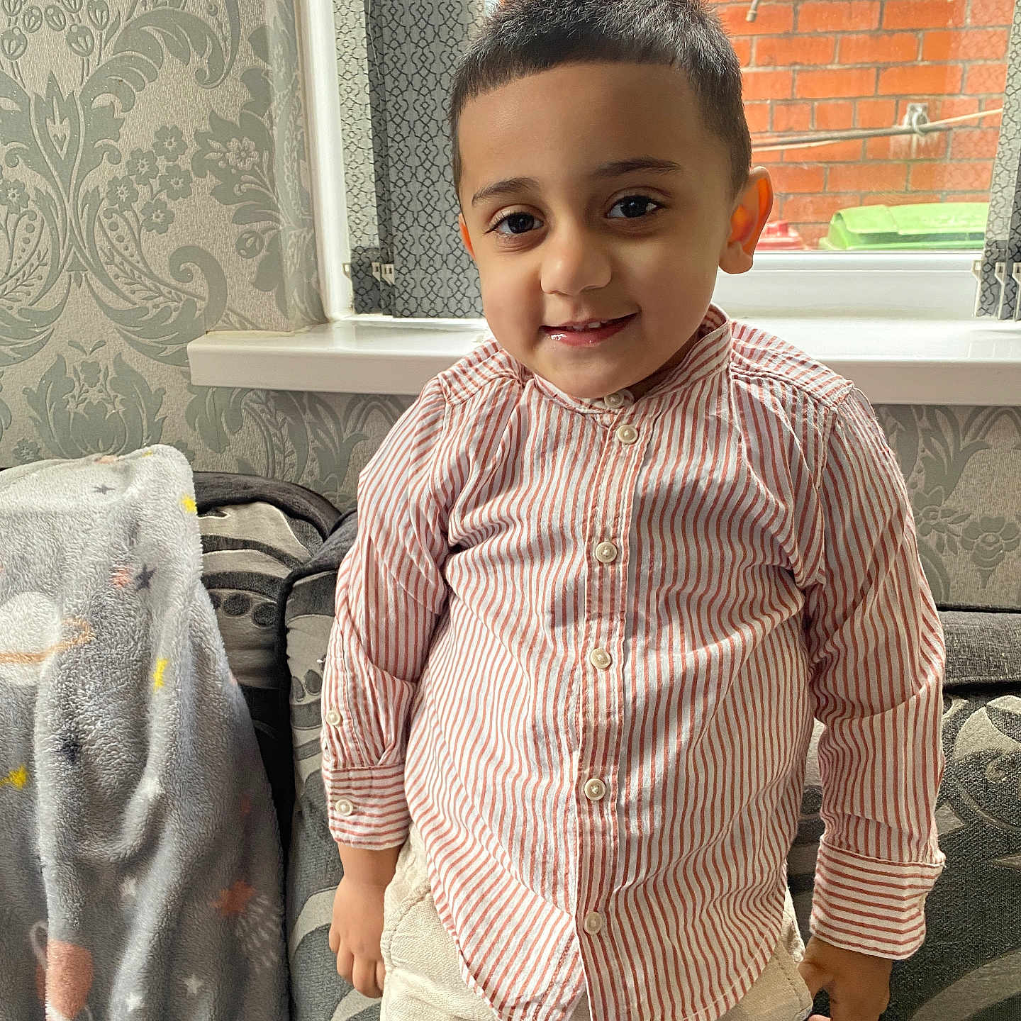 Shahzain joined the competition — help win amazing prizes! blanket, boy, brick_wall, casual_clothing, child, couch, cozy, curtains, furniture, happy, home, indoor, patterned_wallpaper, portrait, short_hair, smiling, standing, striped_shirt, window, young