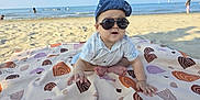 Hung Hiep Ngo joined the competition — help win amazing prizes! baby, beach, blanket, child, clothing, hat, headwear, ocean, outdoor, person, sand, sea, shades, sitting, summer, sunny, toddler, water, wearing_glasses, wearing_hat